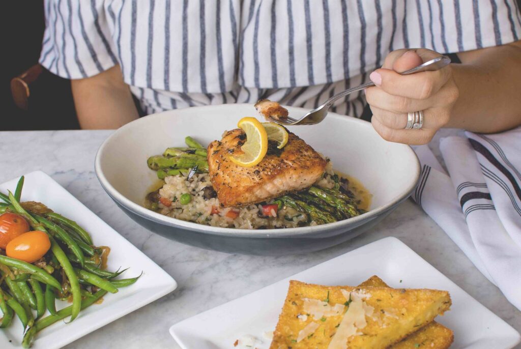 travis-yewell-restauranrs in Orillia woman eating fish-unsplash